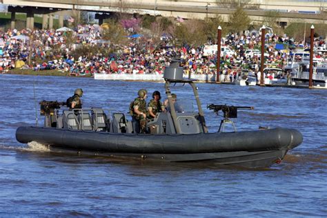 Crowds of spectators watch from the bank of the Ohio River as US Navy (USN) Sailors aboard a ...