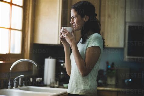 Woman drinking coffee in kitchen stock photo