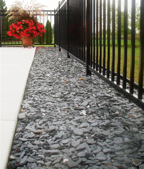 Blue slate chips under a fence and along concrete is decorative and functional. | Landscape ...