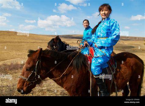 Young Mongolian women in traditional costume (deel) riding horses, Province of Khovd, Mongolia ...