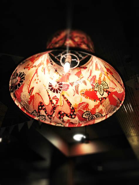 a red and white lamp hanging from the ceiling in a room with dark lighting behind it