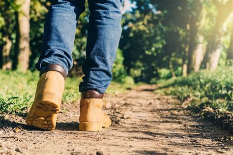 Premium Photo | Feet of an adult wearing boots to travel walking in a green forest travel and ...