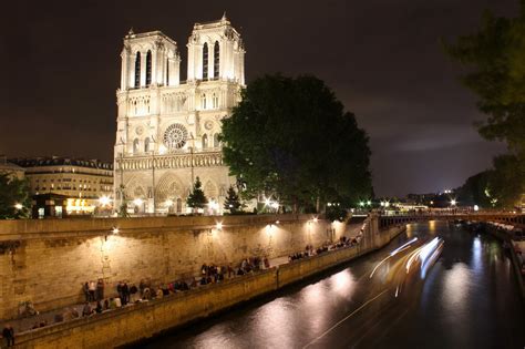 people are standing on the side of a river next to a large cathedral at ...