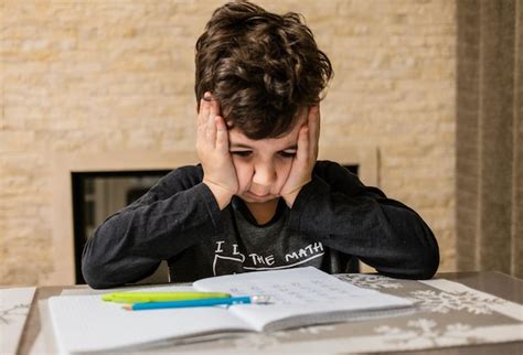 Premium Photo | Cheerful and funny schoolboy solves homework emotionally thinks about how to ...