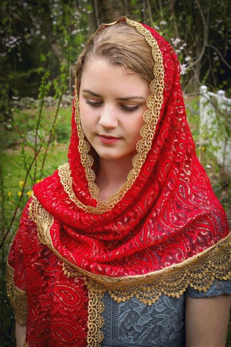 a woman wearing a red shawl and gold trim around her head is looking down