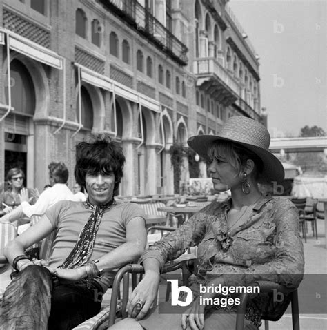 Image of English musician Keith Richards with Anita Pallenberg, sitting outside the