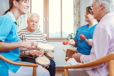 Seniors in nursing home making music with rhythm instruments as ...