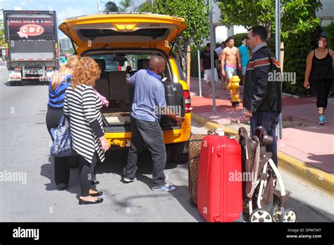 Miami Beach Florida,Ocean Drive,taxi,cab,driver,unloading,luggage,passenger passengers rider ...