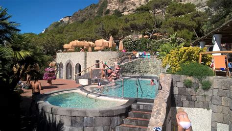 people are playing in an outdoor swimming pool near the mountain side ...