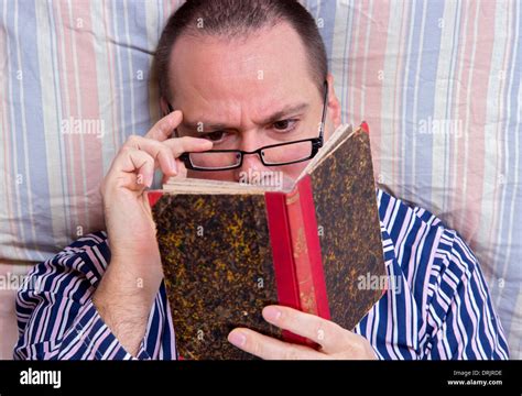 man reading a book in bed Stock Photo - Alamy