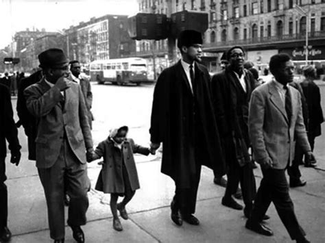 Malcolm X holds the hand of his daughter, Ilyasah Shabazz, as they walk ...