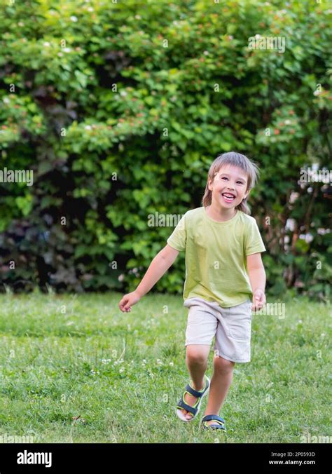 Laughing kid runs on grass lawn at backyard. Happy childhood. Summer ...