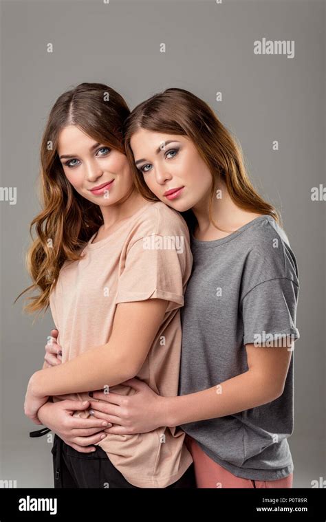 portrait of beautiful twin sisters hugging each other and looking at ...