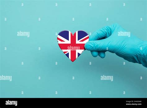 Medical workers hand wearing surgical glove holding United Kingdom flag heart Stock Photo - Alamy