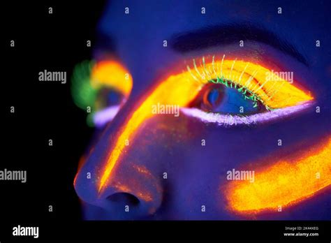 Glowing eyes. A young woman with with neon paint on her face posing Stock Photo - Alamy