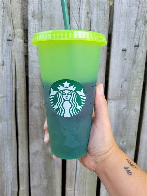 a hand holding up a green starbucks drink with a straw in it's cup