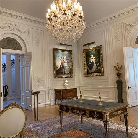 an ornate room with chandelier and paintings on the walls