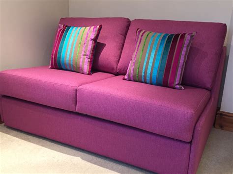 Hot pink armless sofa bed with reversible scatter cushions in Designers Guild Moyka that really ...