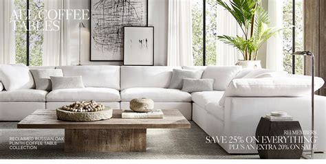 a large white couch sitting in a living room next to a wooden coffee table and potted plant
