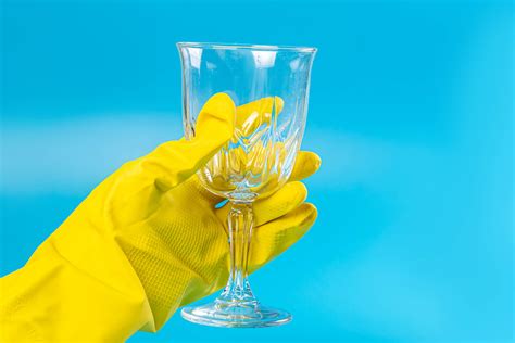 Female hand in a rubber glove holds a wine glass on a blue background - Creative Commons Bilder
