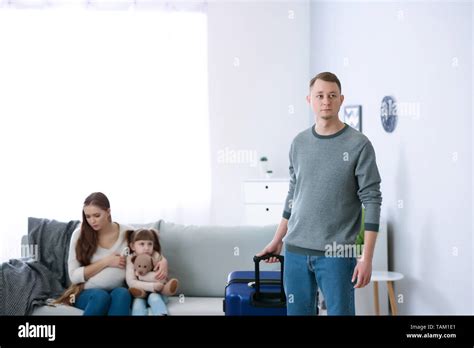 Man with suitcase leaving his family Stock Photo - Alamy