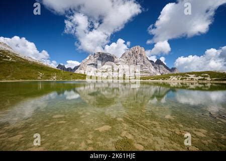 Mount Croda Fiscalina is reflected in the placid waters of the Piani lakes with grass near the ...