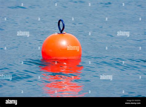 Orange buoy floating in blue water Stock Photo - Alamy