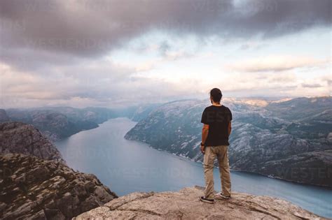 Man standing at edge of cliff at Preikestolen, Norway stock photo