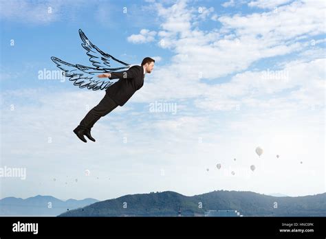 Young businessman with drawn wings flying in sky Stock Photo - Alamy