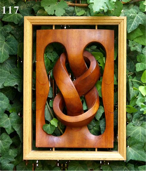 an art piece made out of wood with green leaves around it and in the frame