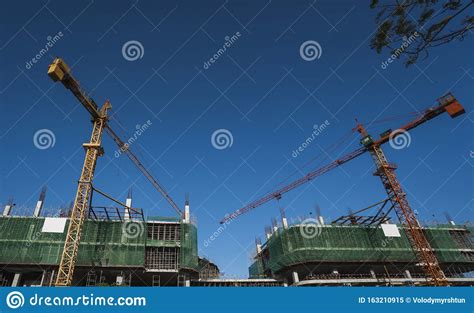 Cranes and Building Construction Site Against Blue Sky. Metal Construction of Unfinished ...