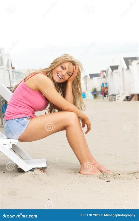 Beautiful Young Woman Sitting At The Beach And Laughing Stock Photos ...