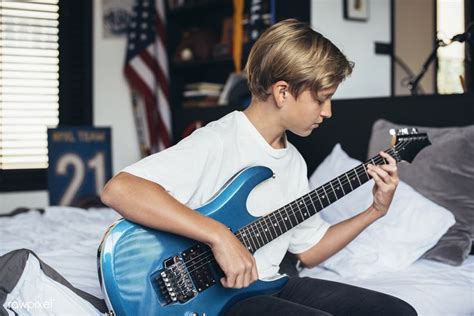 Young boy playing electrical guitar in his bedroom | premium image by ...