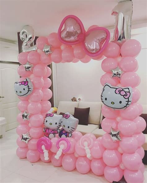 a hello kitty balloon arch in a living room decorated with pink balloons and other decorations