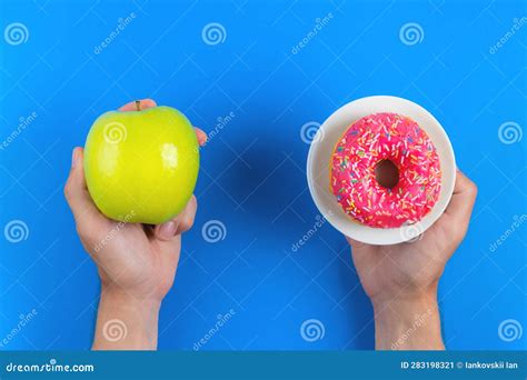 Green Apple and Pink Donut in Male Hands, the Concept of Choosing Health and Unhealthy Food on a ...