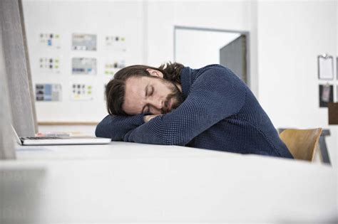 Man sleeping on desk in office stock photo