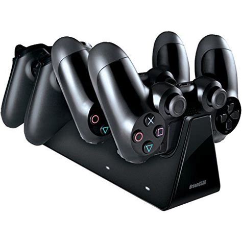 four black video game controllers sitting on top of a charging station with three different buttons