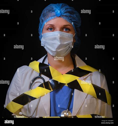 Portrait of a doctor in a white coat on a black background. A nurse wrapped in black and yellow ...