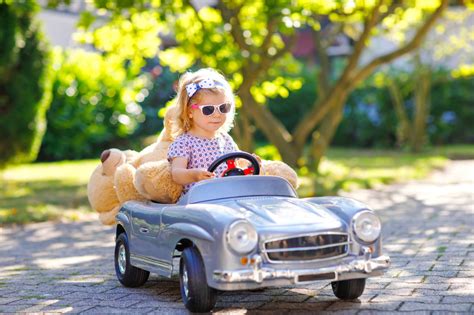 Little adorable toddler girl driving big vintage toy car and having fun ...