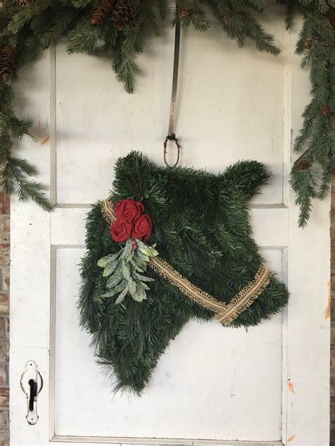 a wreath is hanging on the front door of a house with red roses and greenery