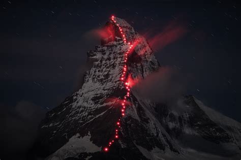 The Matterhorn Lit Up at Night by a Trail of Hikers