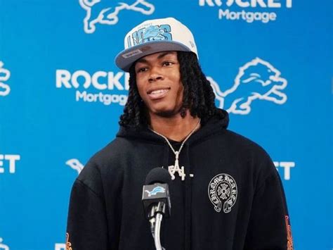 a young man wearing a black jacket and hat standing in front of a ...