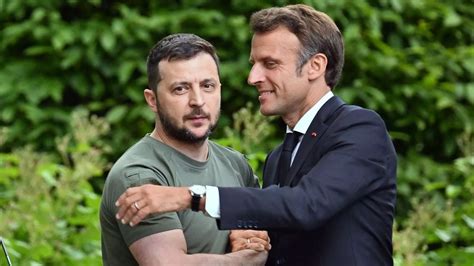 Zelensky looks grim-faced as Macron leans in for an awkward hug in Kyiv ...