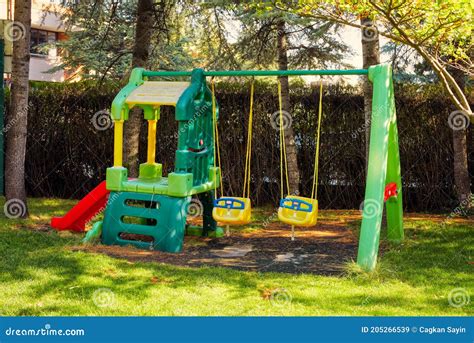 Children Playground with Plastic Swings and Slide on the Grass of a ...