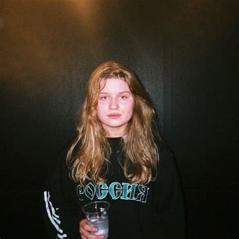 a woman in a black shirt holding a glass and looking at the camera ...