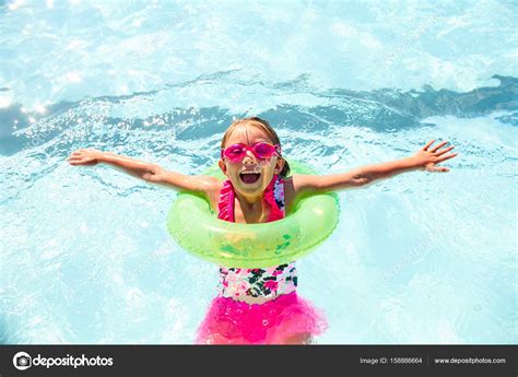 Happy little girl wearing flotation ring in pool Stock Photo by ©Legendaphotos 158886664