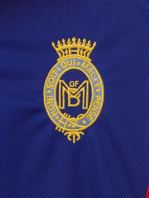 A blue and white polo shirt with school badge embroidered on the chest. Please note: This is a ...