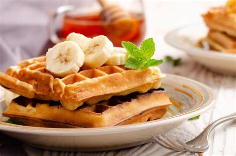 Premium Photo | Belgian waffles served with banana and mint leaf on ...