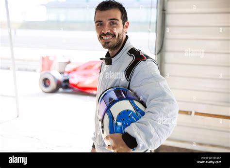 Portrait confident male formula one race car driver holding helmet in ...