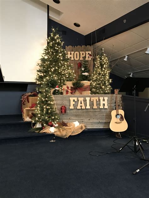 a christmas tree is in front of a sign that says hope, faith and an acoustic guitar